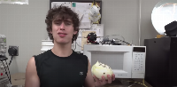 It's a picture of a guy eating an onion, after putting it in a microwave (not a typo)